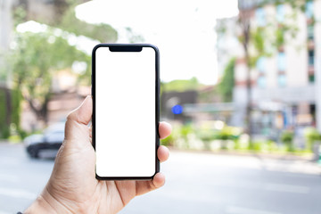 Asian man holding phone mock up left frame at street outdoor have environment city and tree background 
 isolated display for insert screen