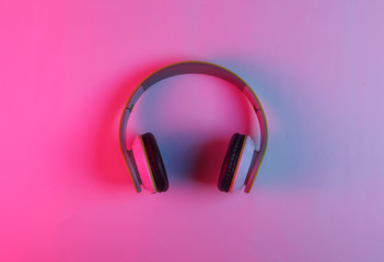 Modern stereo wireless headphones with neon pink blue light. Gradient glow. Top view