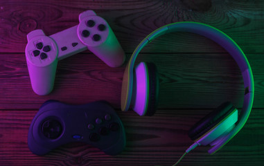 Stereo headphones with retro gamepads. Neon purple green light. Gaming concept. Gradient glow. 80s. Top view