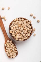 Uncooked dried chickpeas in wooden bowl and spoon