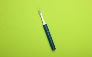 Modern electric toothbrush on green background. Top view. Teeth care. Minimalism