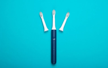 Teeth care. Modern electric toothbrush with nozzles on blue background. Top view. Minimalism