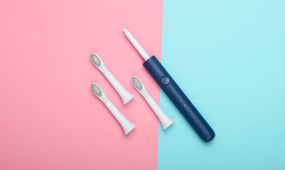 Teeth care. Modern electric toothbrush with nozzles on pink blue background. Top view. Minimalism