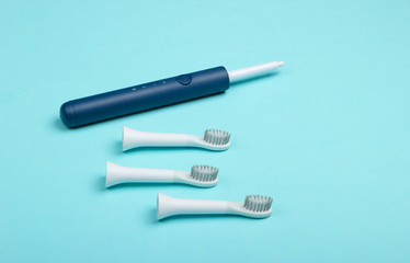 Teeth care. Modern electric toothbrush with nozzles on blue background.