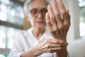 Elderly female patient suffer from numbing pain in hand,numbness fingertip,arthritis inflammation,beriberi or peripheral neuropathies,senior woman massage her hand with wrist pain,rheumatoid arthritis - obrazy, fototapety, plakaty