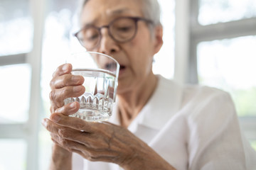 Senior woman holding glass of water,hand shaking while drinking water,elderly patient with hands...
