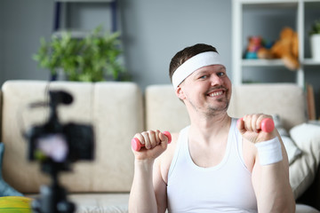 Smiling Man Doing Exercise for Hands with Dumbbell. Blogger Record Aerobic Video on Digital...