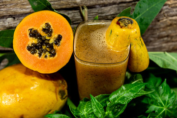 Papaya (Carica papaya) juice between halved fruits and fresh leaves