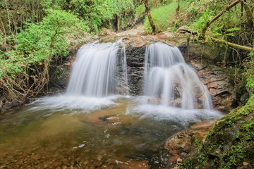 Fototapeta premium view of silky waterfall flowing on cliff rocks around with green forest background, Mae Pan Waterfall, Doi Inthanon National Park, Chiang Mai, northern of Thailand.