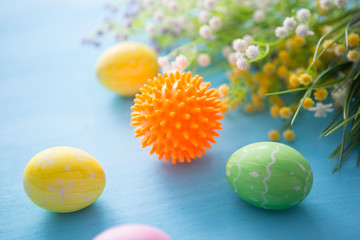 Virus model of Coronavirus disease COVID-19 with colorful easter eggs with flowers on a blue wooden table background