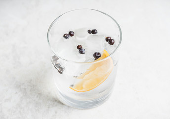 Gin based cocktail with lemon slice and juniper berries. Selective focus. Shallow depth of field.