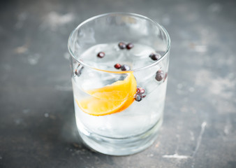 Gin based cocktail with lemon slice and juniper berries. Selective focus. Shallow depth of field.