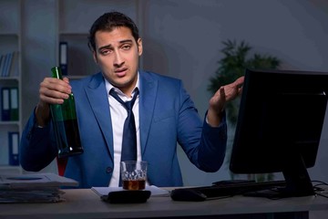 Alcohol addicted businessman working late in the office