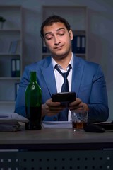 Alcohol addicted businessman working late in the office