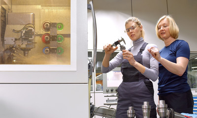 A young trainee receives tuition from her trainer. Both women work as computerized  numerical...