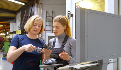 A young trainee receives tuition from her trainer. Both women work as computerized  numerical...