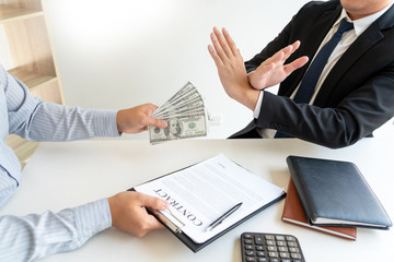 Businessman rejecting money or refusing money form of dollar bills to take the bribe to agreement contract, anti bribery and corruption concept.