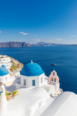 Beautiful Oia town on Santorini island, Greece. Traditional white architecture and greek orthodox churches with blue domes over the Caldera, Aegean sea. Scenic luxury travel background.