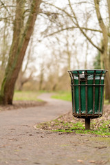 Obraz na płótnie Canvas A bin standing beside a path in a park in Twickenham, West London, England