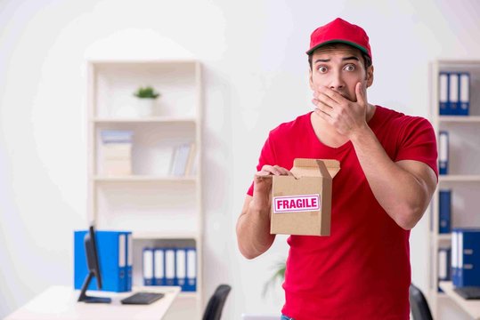 Young male courier delivering postbox to the office