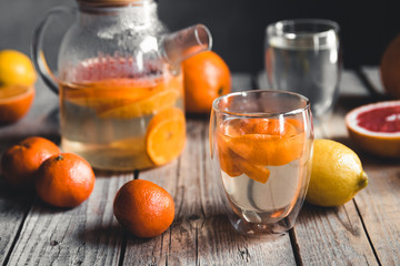 Citrus tea in a transparent teapot on a table with grapefruit and on a wooden table. Healthy drink.
