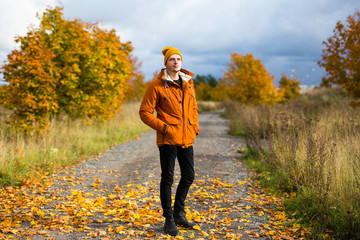 full length portrait of young man posing in autumn park