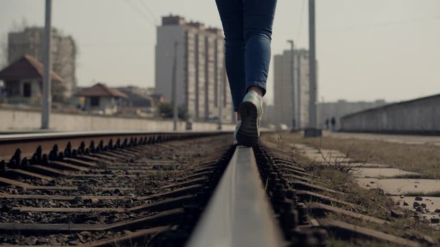 Girl Walks On Railroad Tracks .Tourist Legs Walking On Railway After Canceled Tram Public Transport Middle Of Rail.Lonely Woman Feet In Jeans Walking On Rail Road When Train Or Tram Cancelled