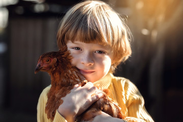 Portrait of a boy hugging a chicken.