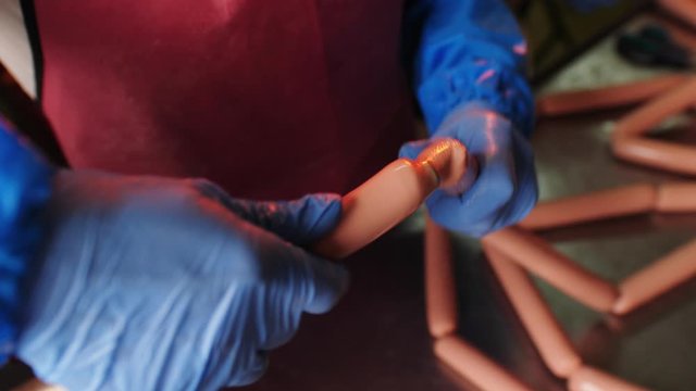 worker in gloves fills casings with meat mass in workshop
