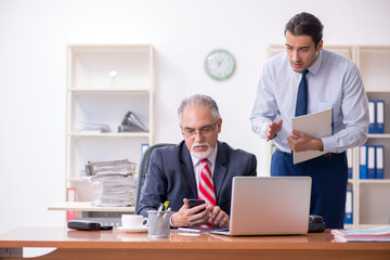 Old boss and young male employee in the office