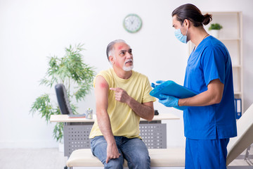 Fototapeta premium Injured old man visiting young male doctor traumatologist