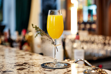 glass glass with orange alcoholic drink with a sprig of grass stands on a marble table
