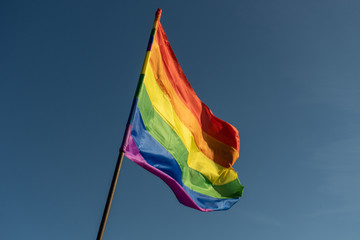 Gay rainbow flag on a sunny summer day with blue sky