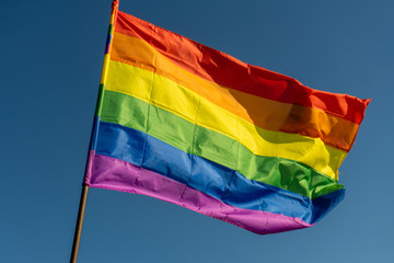 Gay rainbow flag on a sunny summer day with blue sky