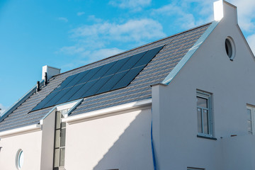 Newly build house in the Netherlands with solar panels attached on the roof against a sunny sky...