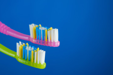 green and pink toothbrush on blue background, couple. place for text