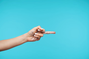 Beautiful young woman's hand with glitter being raised up while pointing aside with exposed middle...