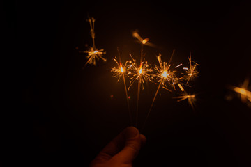 Hand holding sparklers in dark