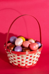 Fototapeta na wymiar Easter eggs in basket isolated on red