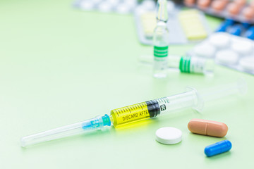 Assorted medical drugs and syringe on light green background, with copy space. Coronavirus COVID-2019 vaccine and protection.