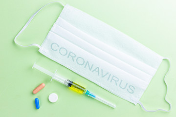 Medical masks, pills and syringes lie on a light green background top view.