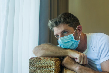 covid-19 virus lockdown - sad and worried man in medical mask thinking and feeling scared in...