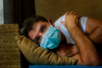 covid-19 virus lockdown - sad and worried man in medical mask thinking and feeling scared in...