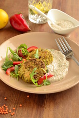 Lentil fritters with zucchini. Served with fresh vegetables and sauce, vertical