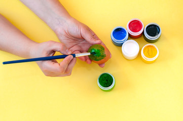 Woman hand painting easter egg on yellow background