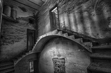Obraz premium Escaleras en la penumbra en habitación sucia de casa abandonada.