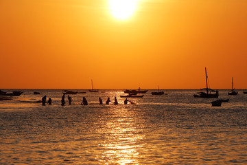 Zanzibar sunset with fisherman and boats silhouettes