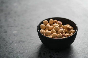 roasted hazelnuts in black bowl on terrazzo countertop