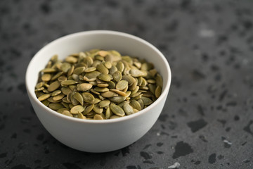 pumpkin seeds in white bowl on terrazzo countertop