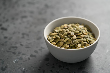 pumpkin seeds in white bowl on terrazzo countertop